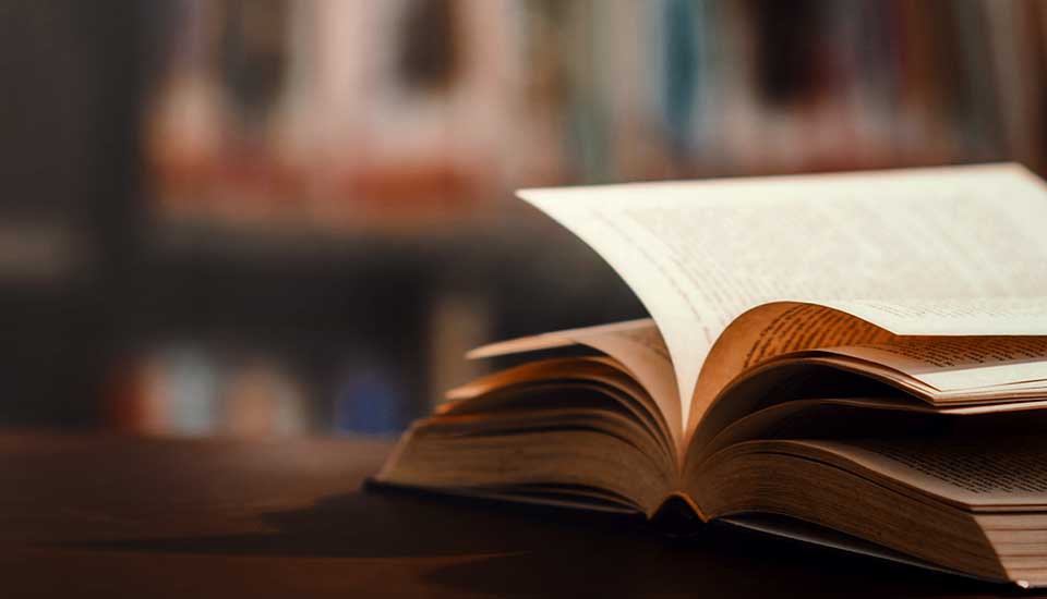 Bok ligger uppslagen på ett bord i ett bibliotek